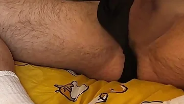 A hairy dude jerks his thick cock while watching porn on his bed. He strokes himself hard and fast until he blows his load all over himself.